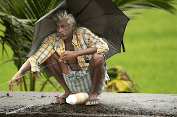 Man wearing Indian Traditional Lungi fishing with a simple line, 2019